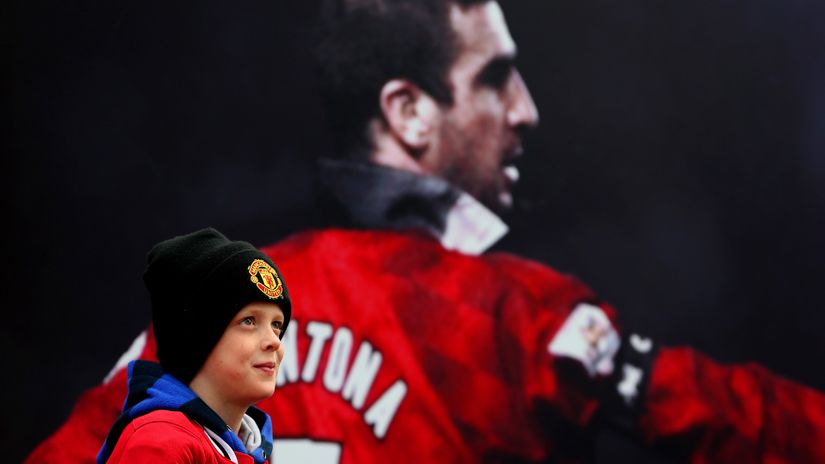 A fan poses next to a poster of Cantona at Old Trafford (©Jan Kruger/Getty Images)