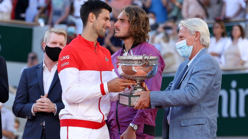 Borg delivers the Rolan Garros trophy to Djokovic, with Tsitsipas in the back (©John Berry/Getty Images) 
