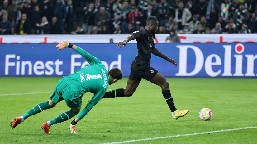  Marcus Thuram of Borussia Monchengladbach scores their side's third goal past Gregor Kobel of Borussia Dortmund (©Christof Koepsel/Getty Images)
