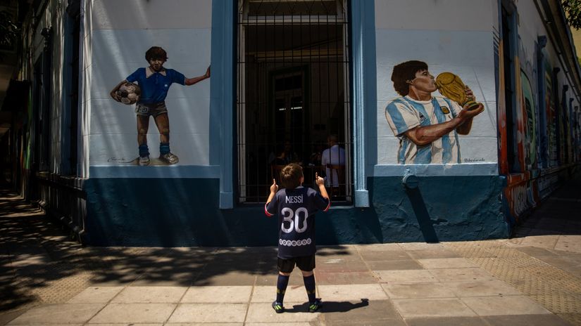 A boy poses for a photo in front of a mural of Diego Armando Maradona in Buenos Aires (©Tomas Cuesta/Getty Images)