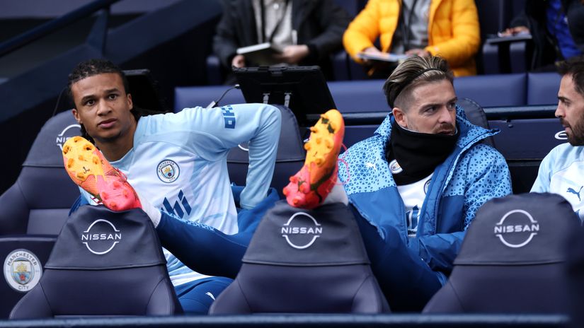 Grealish sitting on the bench with Ake and Bernardo Silva (© Alex Livesey/Getty Images)