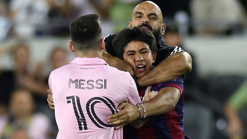 Yassine Chueko pulls a fan, who ran onto the pitch, away from Messi (©Harry How/Getty Images)