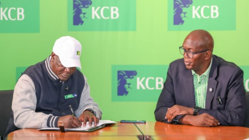 Robert Matano (L) signs his contract as KCB FC patron Azu Ogola looks on© KCB