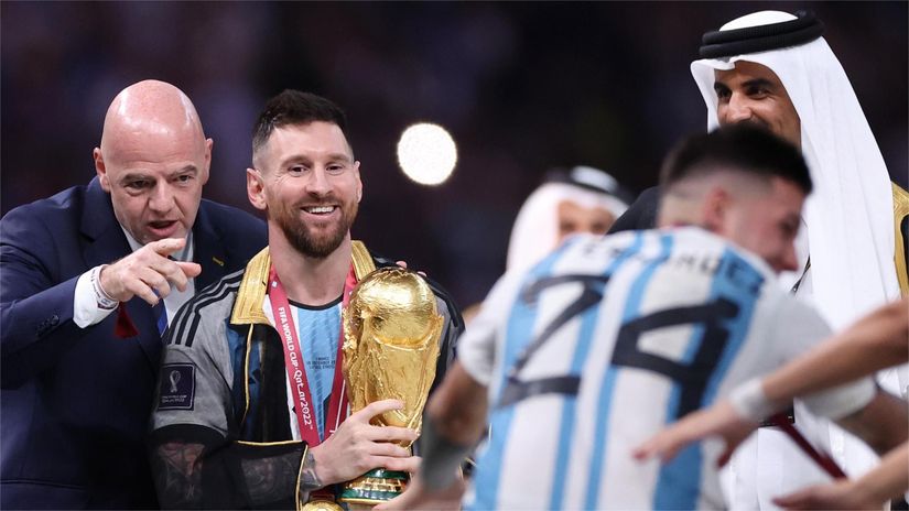 FIFA president Gianni Infantino with Leo Messi as he holds the 2022 WC trophy (©Catherine Ivill/Getty Images)