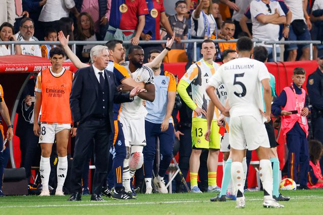 A member of Real Madrid staff tries to stop Rudiger from going at the ref (©AFP)